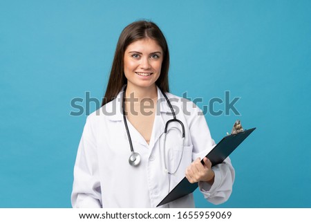 Young woman over isolated blue background with doctor gown and holding a folder