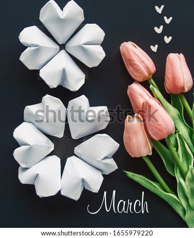 color white paper hearts shape figure eight 8 on dark background with tulips flowers International Women's Day card