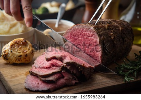 sliceing roasted eye of round beef with knife Royalty-Free Stock Photo #1655983264
