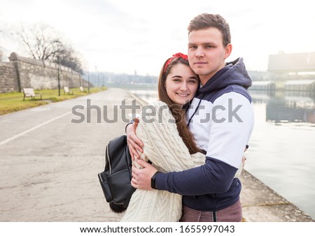 Young couple in love outdoor. Cute couple of young people is walking in spring park. Happy guy and girl. They looks at camera. Travelers