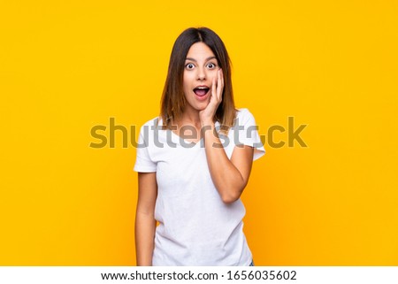 Young woman over isolated yellow background surprised and shocked while looking right