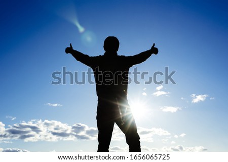 silhouette against a blue sky with arms and fingers raised up. business success concept. achievements in sports