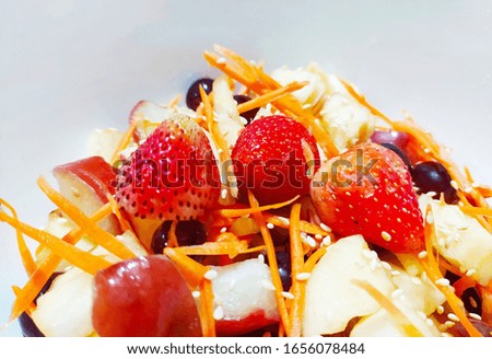 Close up of fruit salas with strawberry, apple,  grapes, white sesame  and sliced carrot