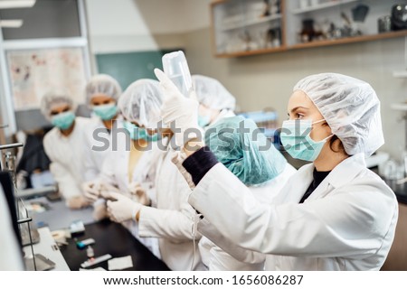 Team of pharmacists developing parenteral antibody antivirus.Pharmaceutical development of a new vaccine.Parenteral antibiotic safety control test examination in the cleanroom.Virus epidemic concept Royalty-Free Stock Photo #1656086287