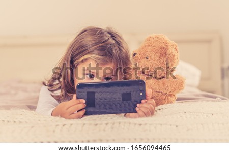 Little caucasian girl on mobile phone playing, watching cartoons or chatting with family. Cute blonde toddler using smart phone In Education and technology, digital generation and phone addiction.