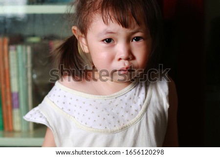 The unhappy little girl standing on the chair