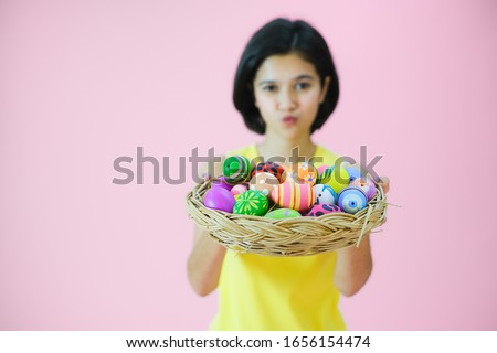 Portrait beautiful young girl wearing yellow tank top shirt with painted eggs on pink background, Happy easter day