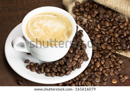 Coffee beans with cup on a brown wooden table