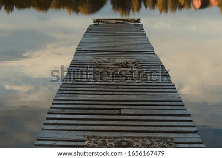 Photo of a pier going into the distance on the lake. Calm water, cloud reflections.