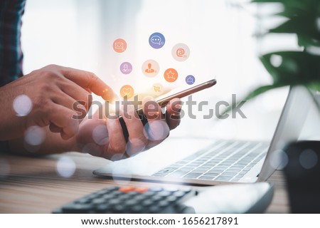 Social media interactions on mobile phone, concept with notification icons of like, message, email, comment and star above smartphone screen, person hands holding device, internet digital marketing Royalty-Free Stock Photo #1656217891