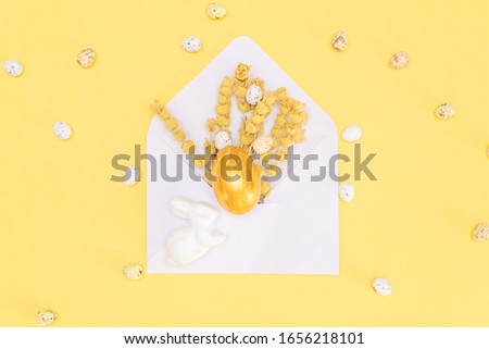 Golden chocolate Easter eggs and chocolate bunny with copy space on a yellow background.