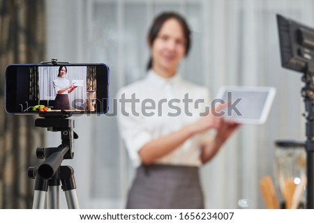 vlogger recording video for food channel. Female vlogging with her mobile phone mounted on a tripod and a light stand. Royalty-Free Stock Photo #1656234007