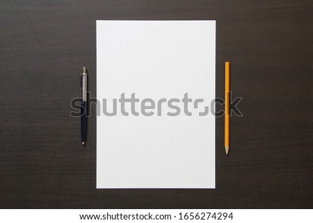 Template of white paper with pen and pencil on dark wenge color wooden background. Concept of business plan and strategy. Stock photo with empty space for text and design.