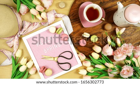 Hello Spring theme creative layout concept flat lay tea break with pink tulips and lisianthus flowers, sun hat on wooden table background, wih felt letter board. Royalty-Free Stock Photo #1656302773