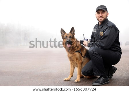 Male police officer with dog patrolling city street Royalty-Free Stock Photo #1656307924