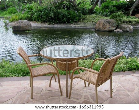 Table and chairs on an outside patio by a pond