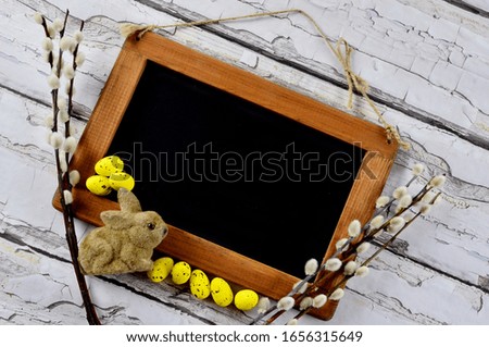Spring greeting card with mock up. Easter eggs with catkins  and easter bunny on the vintage wooden background. Top view.