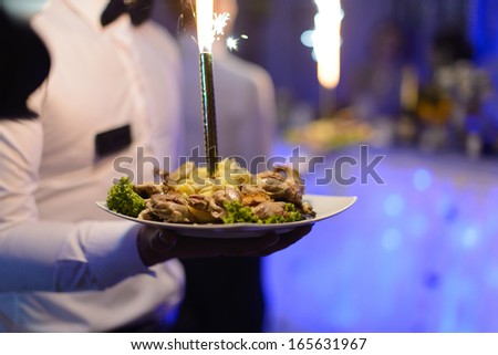 waiters holding plates with meat and fire