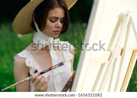 young easel woman paints a picture in the fresh air