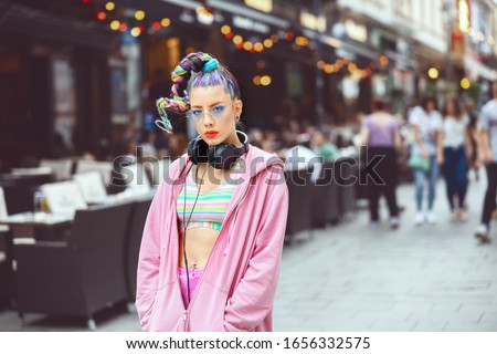 Portrait of cool hipster young woman with trendy eyeglasses and street style clothes in city street – Funky teenage girl with avant garde fashion hair – new generation lifestyle concept Royalty-Free Stock Photo #1656332575