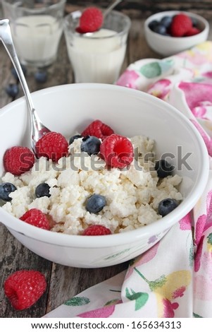 Fresh cottage cheese with berries and milk on a wooden background.