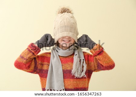 Cute little boy in winter clothes on color background