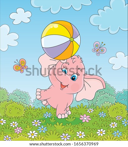 Little pink elephant playing with a big colorful ball on green grass among flowers and flittering butterflies on a summer field on a sunny warm day, vector cartoon illustration