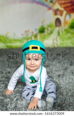 First birthday cute baby boy wearing a St. Patrick's Day hat. Cartoon fairy house on background
