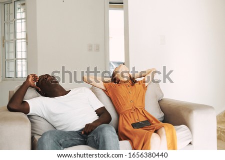 A man of African appearance on a couch tilted her head back