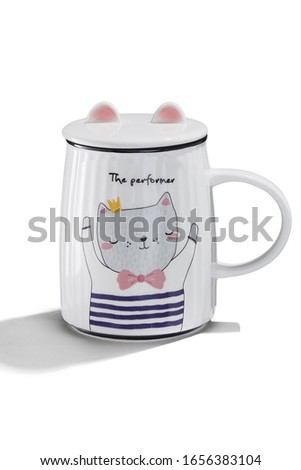 Subject shot of a white ceramic mug with a picture of a cat in a sailor's striped vest, a cover with cat's ears and lettering "The performer". The cute cup is isolated on the white background.