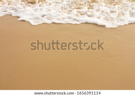 White bubbles of wave crash the sandy beach for background