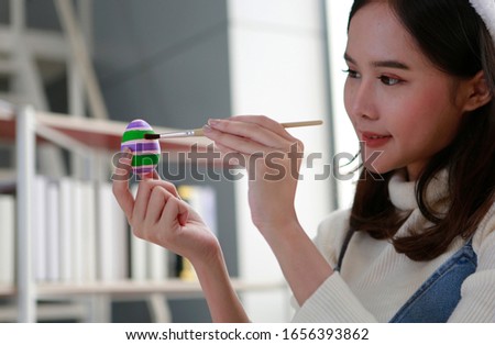Close-up photo portrait of young Asian lovely cute beautiful woman painting colorful Easter egg in hand. Happy Easter concept. Bangkok Thailand South east Asia