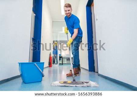 Busy cleaner man mopping the floor in a hall Royalty-Free Stock Photo #1656393886