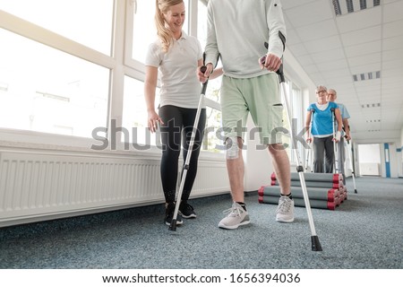 People in rehabilitation learning how to walk with crutches after having had an injury Royalty-Free Stock Photo #1656394036