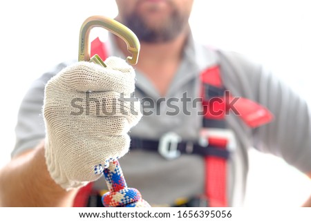 gloved hand with an open carabiner for mountaineering. industrial mountaineering system for insurance worn by a man