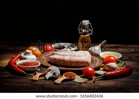 Many different spices, vegetables and ingredients, and fresh raw barbecue sausages for the family.