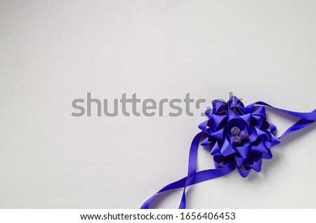 Decorative blue flower on a light background. Top view of a flower woven from a ribbon. Eye level shooting. Selective focus. Close-up.
