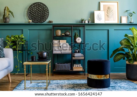 Stylish interior of living room with gray sofa, design pouf, coffee table, plants, pillow and elegant personal accessories. Wood panelling with shelf. Modern home decor. Mock up poster frame. Template Royalty-Free Stock Photo #1656424147