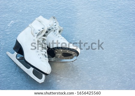 old white figure skates lie on ice, winter outdoor activities, sports health in winter, space for text	