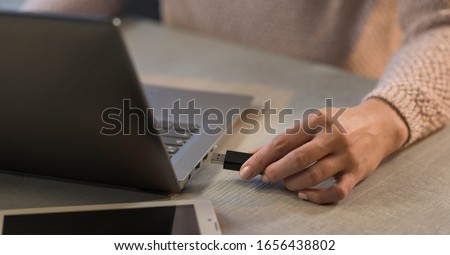 Woman plugging a USB drive into her laptop, technology and data storage concept Royalty-Free Stock Photo #1656438802