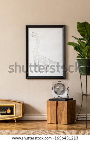 Retro interior design of living room with plants in green pot, vintage radio, wooden cube, lamp and black mock up picture frame on the beige wall. Minimalistic concept of home decor. Template. 