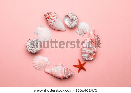 Summer concept background. White seashells, red starfish isolated on trendy Living Coral pastel color backdrop. Shells in shape frame with copy space