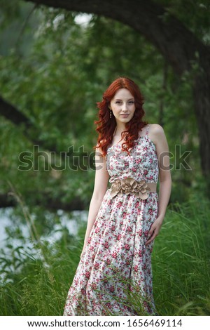 The red-haired girl walks in the forest. Summer photo shoot