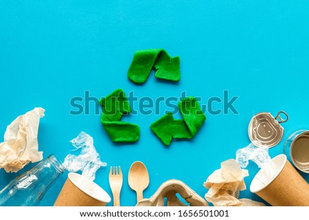 Green recycle icon near plastic, paper, glass waste on blue background top-down copy space