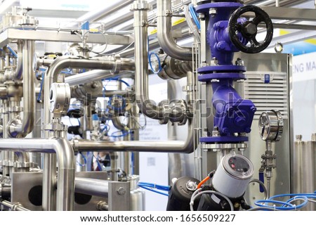 Stainless steel pipes in a food factory. Stainless pipe fittings. Tubular heat exchangers. Food pumps. A fragment of a dairy plant. Royalty-Free Stock Photo #1656509227