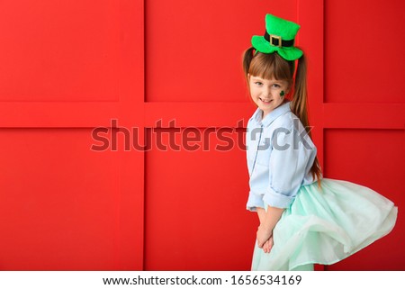 Funny little girl on color background. St. Patrick's Day celebration