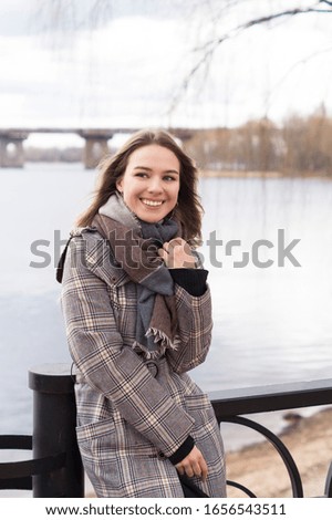 
Smiling beautiful girl in a park in a fashionable coat. Checkered autumn coat