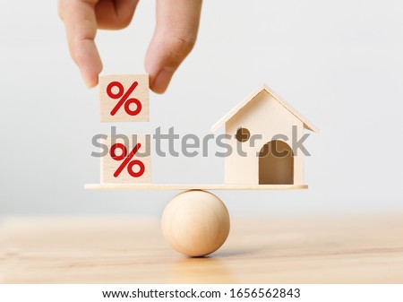 Interest rate financial and mortgage rates concept. Wooden home and hand putting cube block shape with icon percent on wood scales Royalty-Free Stock Photo #1656562843