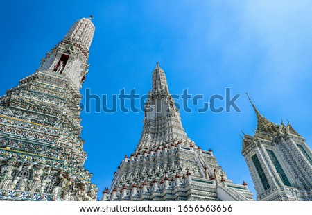 View from below of a group of pagodas inside the Temple of Dawn under blue sky of Bangkok, Thailand