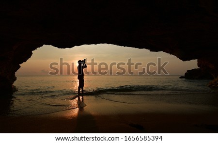Man standing using camera To take a picture in front of the cave in the morning at sunrise